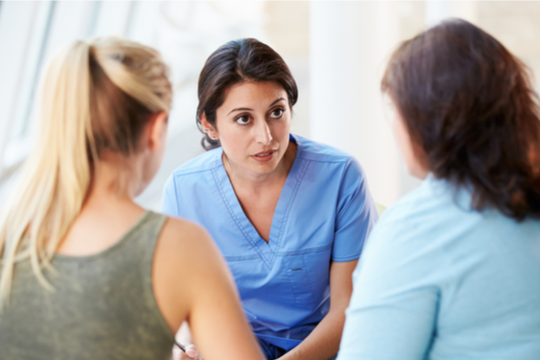 A female nurse talks earnestly with family members.