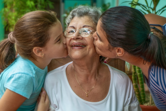 Two people kiss an elderly woman